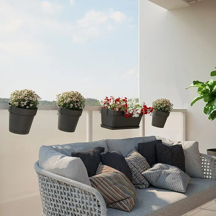 Artevasi Capri Geländertopf - Außenmaß (Ø x H): 20 x 21,5 cm, Kunststoff, Grün, Matt - Ein graues Outdoor-Sofa mit bunten Kissen und hängenden Blumenkästen mit bunten Blumen, die eine einladende Atmosphäre schaffen.