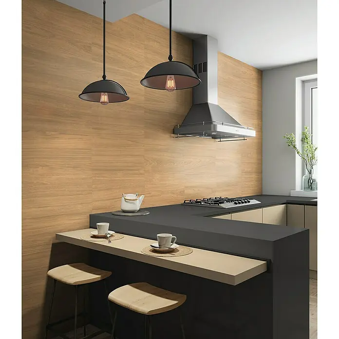 Pavimento porcelánico Sherwood - 30 x 60 cm, Roble, Mate - Isla de cocina con taburetes y luces colgantes. Diseño elegante con paneles de madera, campana extractora y mobiliario moderno.