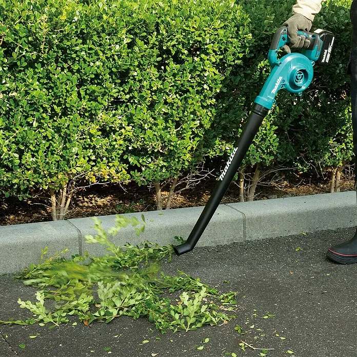 Makita LXT 18V Akku-Gebläse DUB186SFX1 - 1 Akku, 3 Ah, Blasgeschwindigkeit: 68 m/s - Der Makita Akku-Laubbläser im Einsatz, um Blätter und Gartenabfälle von einer asphaltierten Fläche zu entfernen.