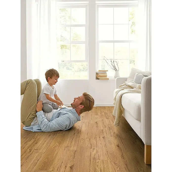 Decolife Designboden Freestyle Access Oak Rustic Gold - 1.220 x 185 x 8,5 mm, Landhausdiele, Oak Rustic Gold - Ein Vater liegt mit seinem Kind auf einem hellen Holzboden und spielt, während das Sonnenlicht durch die Fenster scheint.