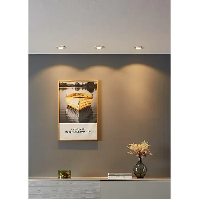 Eglo Downlight LED empotrable Saliceto - Blanco cálido, Diámetro: 8,8 cm, Blanco, 3 ud. - Tres focos empotrados blancos en un techo, proyectando luz cálida sobre una pared gris con un cuadro enmarcado.