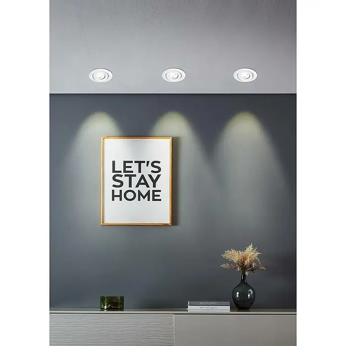 Eglo LED-Einbauleuchten-Set rund SALICETO MINI-PUCK 1 - 4,2 W, Ø x H: 7,7 x 2,3 cm, Weiß, Warmweiß - Drei LED-Deckeneinbaustrahler erhellen eine graue Wand mit einem gerahmten "Let's Stay Home"-Bild und einer stilvollen Kommode mit Deko.