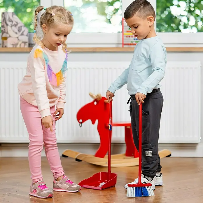 Klein Vileda Kinder-Reinigungs-Set - 2 -tlg. - Zwei Kinder spielen mit einem roten Kehrset mit Besen und Kehrschaufel auf einem Holzboden.