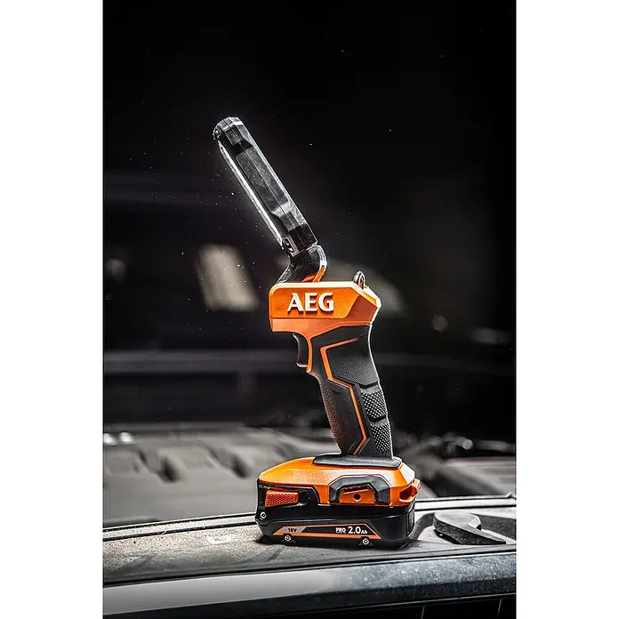 AEG Pro 18V LED-Akkustrahler BSL 18 - 18 V, Ohne Akku, 800 lm - Orange-schwarze AEG Akku-Arbeitsleuchte auf schmutziger Oberfläche.