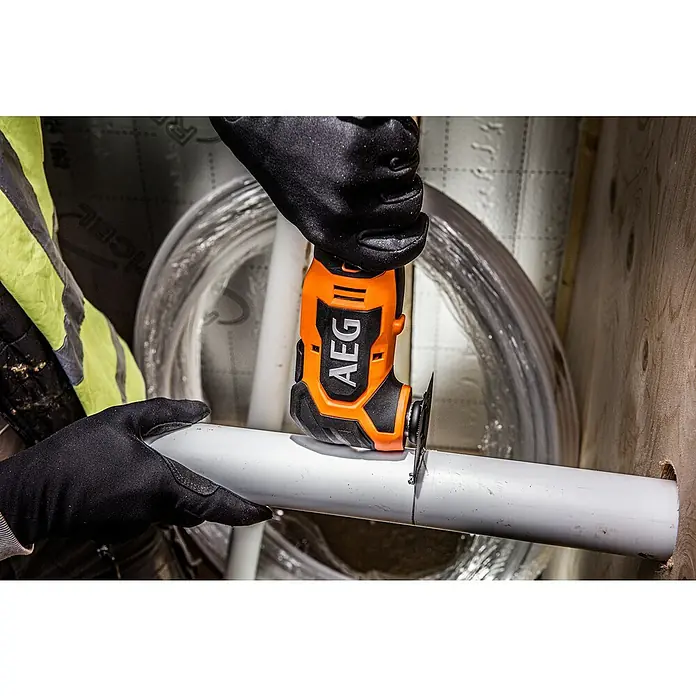 AEG Pro 18V Akku-Multifunktionswerkzeug BMT 18BL - 18 V, Ohne Akku, Leerlaufschwingzahl: 20.000 /min - Person in Handschuhen schneidet ein weißes Rohr mit einem orange-schwarzen AEG-Multifunktionswerkzeug.