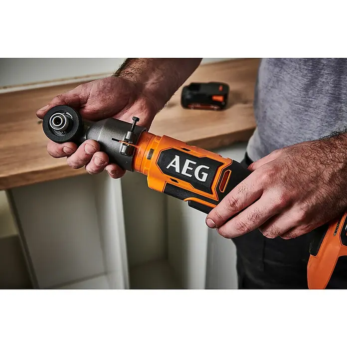 AEG Pro 18V Akku-Winkelbohrschrauber BSS 18SRABL - 18 V, Ohne Akku, 150 Nm - Mann hält einen orange-grauen AEG Akku-Winkel-Schlagschrauber. Eine Batterie ist im Hintergrund.