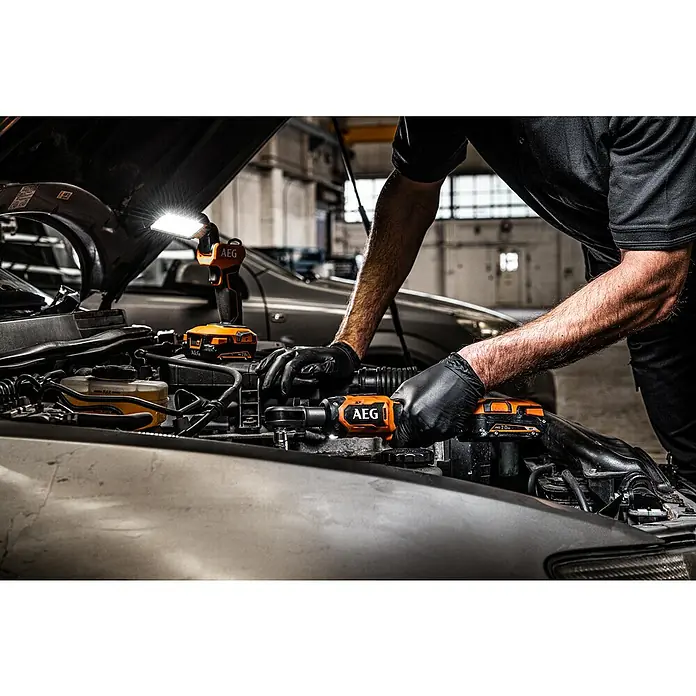 AEG Pro 18V Akku-Ratschenschrauber BSS 18R38BL - 18 V, Ohne Akku, Max. Drehmoment: 74 Nm - Mechaniker verwendet orange-schwarze AEG Akkuknarre und Arbeitsleuchte an einem Automotor.
