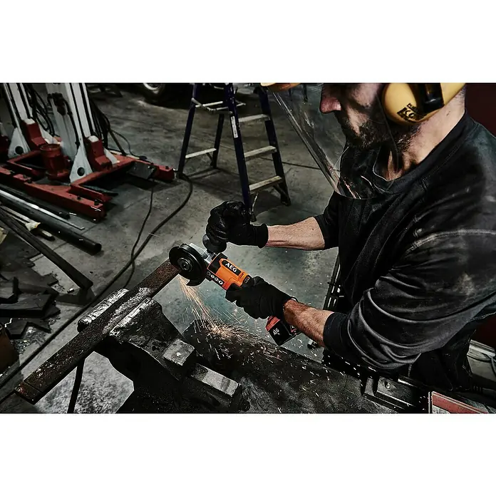 AEG Pro 18V Akku-Winkelschleifer BEWS 18-125X2-0 - 18 V, Ohne Akku, Durchmesser Scheibe: 125 mm - Mann in Schutzkleidung schneidet Metall mit orange-schwarzem AEG Winkelschleifer, Funken sprühen.