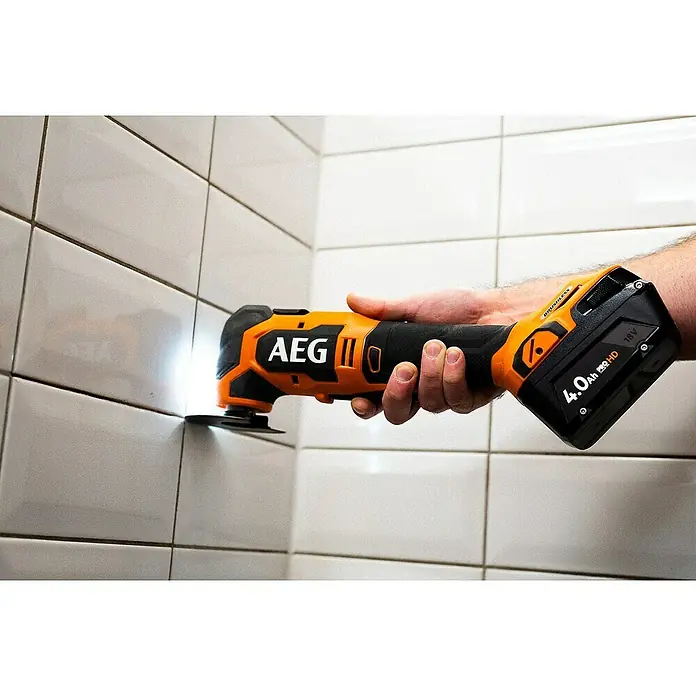 AEG Pro 18V Akku-Multifunktionswerkzeug BMT 18BL - 18 V, Ohne Akku, Leerlaufschwingzahl: 20.000 /min - Eine Person benutzt ein orange-schwarzes AEG Multifunktionswerkzeug mit hellem LED-Licht zur Bearbeitung von Fugen.