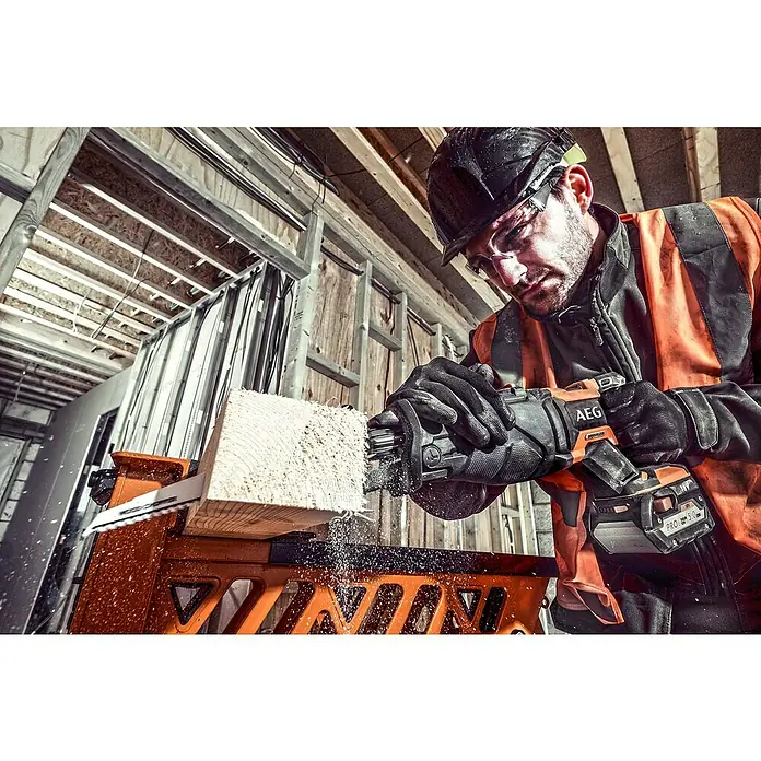 AEG Pro 18V Akku-Säbelsäge BUS 18BL2 - 18 V, Ohne Akku, Leerlaufhubzahl: 0 /min - 3.200 /min - Arbeiter in Schutzkleidung schneidet Holz mit orange-schwarzer AEG Säbelsäge, Sägemehl entsteht.