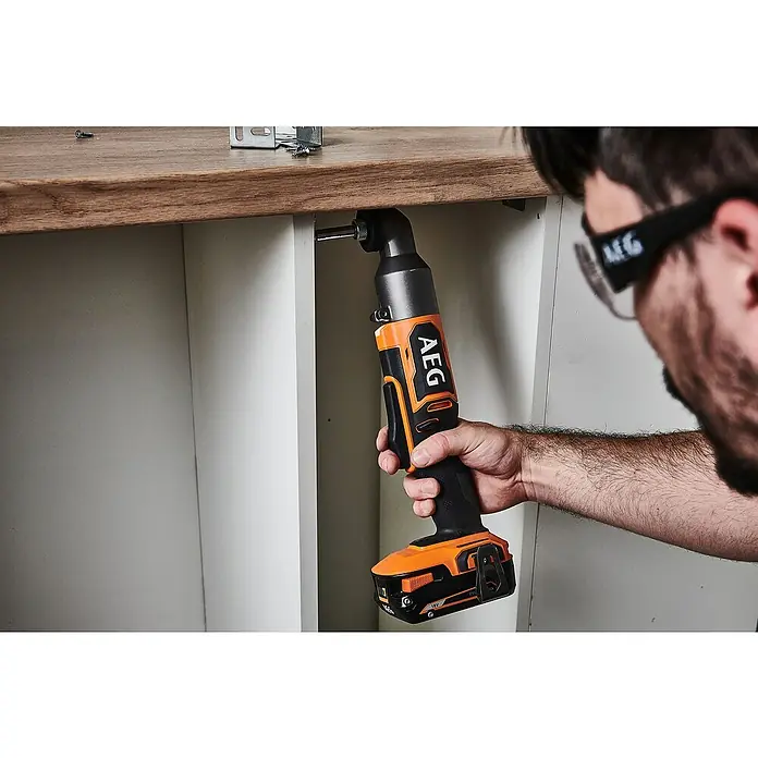 AEG Pro 18V Akku-Winkelbohrschrauber BSS 18SRABL - 18 V, Ohne Akku, 150 Nm - Eine Person verwendet einen orange-schwarzen AEG Winkel-Schlagschrauber, um eine Schraube in ein Holzregal zu befestigen.