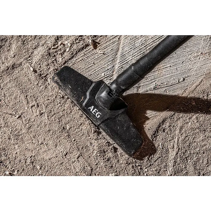 AEG Akku-Handstaubsauger BHSS18C-0 - Ohne Akku, Behältervolumen: 860 l - Schwarzer AEG Staubsaugerkopf auf staubigem, sandigem Boden mit Holzspänen.