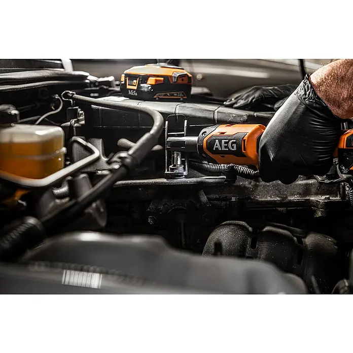 AEG Pro 18V Akku-Ratschenschrauber BSS 18R14BL - 18 V, Ohne Akku, ¼″ Außenvierkant, 61 Nm - Behandschuhte Hand benutzt einen orange-schwarzen AEG Akku-Ratschenschrauber an einem Automotor. Ein AEG Akku ist ebenfalls sichtbar.