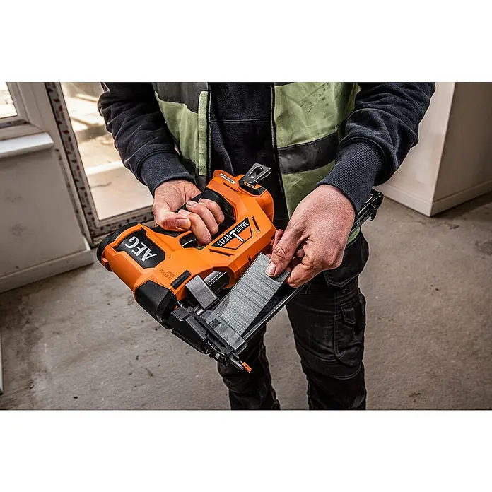 AEG Pro 18V Akku-Nagler B18BN18-0 - 18 V, Ohne Akku, Länge Nagel: 16 mm - 54 mm - Person lädt orange-schwarze AEG Nagelpresse mit einem Nagelstreifen für den Gebrauch.
