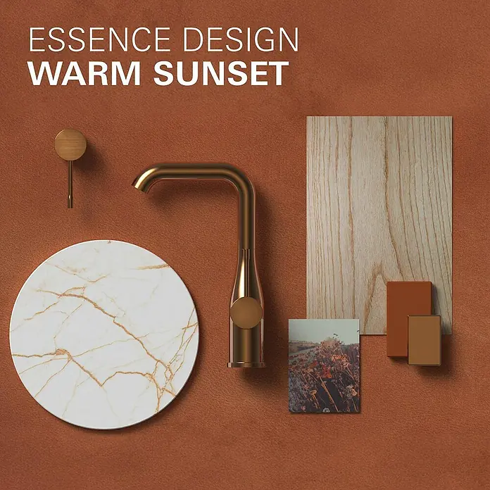 Grohe Essence Waschtischarmatur M - Wandmontage, Warm Sunset, Matt - Nahaufnahme eines luxuriösen, goldfarbenen Wasserhahns, umgeben von Marmor, Holz und Farbmustern für ein elegantes Baddesign.