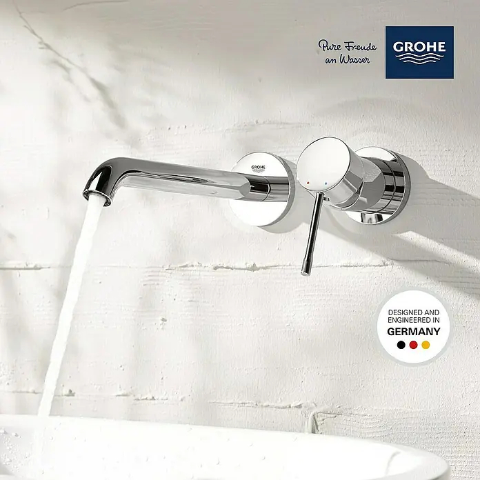 Grohe Essence Waschtischarmatur L - Wandmontage, Chrom, Glänzend - Nahaufnahme einer glänzenden Grohe Armatur, an der das Wasser läuft, mit dem Slogan "Designed and Engineered in Germany".