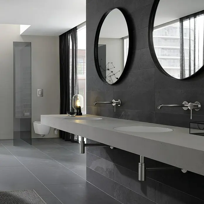 Grohe Essence Waschtischarmatur M - Wandmontage, Supersteel, Matt - Modernes Badezimmer mit grauem Waschtisch, zwei runden Spiegeln und Armaturen. Elegantes Design für ein stilvolles Ambiente.