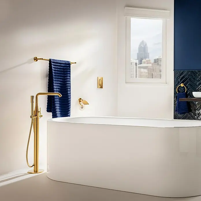 Grohe Essence Badewannenstandarmatur - Höhe: 88,4 cm, Cool Sunrise, Matt - Luxuriöses Badezimmer mit freistehender Badewanne, goldener Armatur und blauen Akzenten für ein elegantes Ambiente.