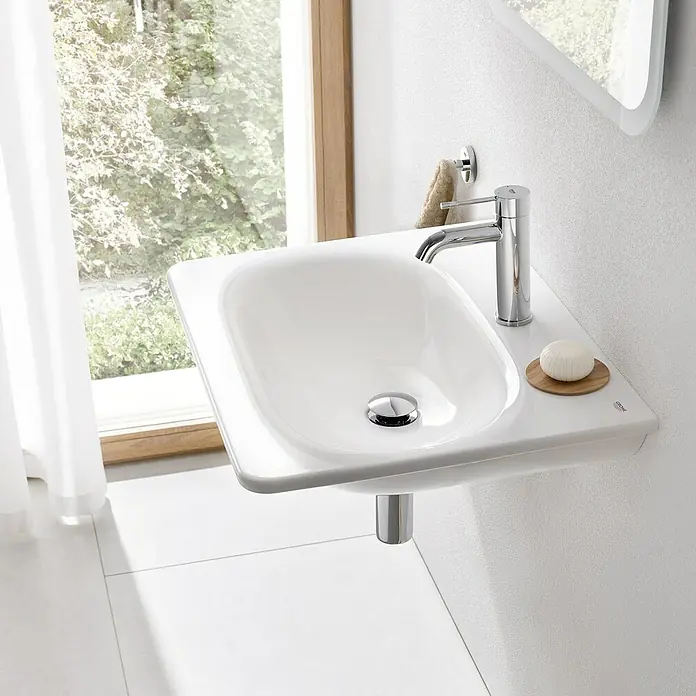Grohe Essence New Waschtischarmatur S-Size - Hochdruck, Verchromt, Glänzend - Nahaufnahme eines stilvollen, wandmontierten Waschbeckens mit Armatur und Seife. Das Design ist modern und minimalistisch, ideal für ein elegantes Badezimmer.