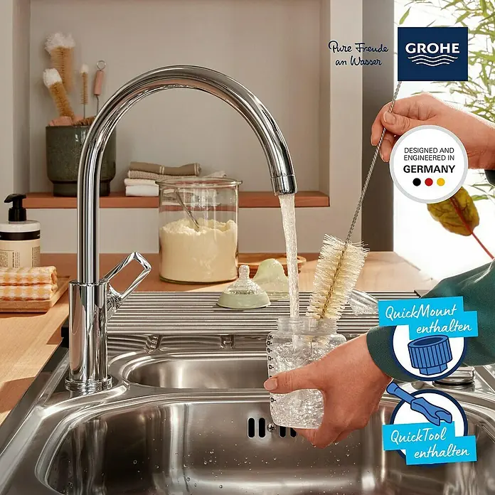 Grohe Start Loop Spültischarmatur - Chrom, Glänzend - Das Bild zeigt eine GROHE Küchenarmatur, die Wasser in eine Babyflasche füllt, während sie mit einer Bürste gereinigt wird.