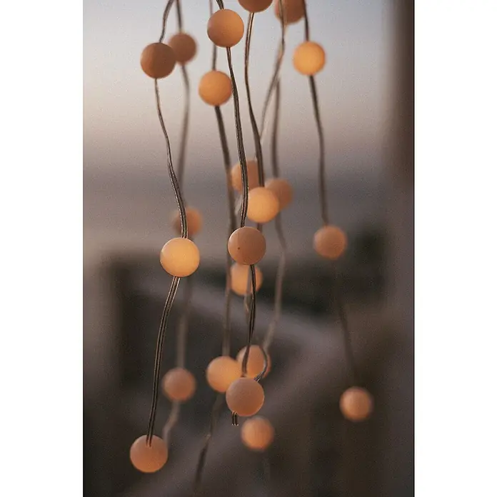 New Garden Lámpara decorativa solar Griselda - Para exterior, 10 cm, Blanco cálido - Primer plano de luces de hadas con esferas delicadas y brillantes, creando un ambiente acogedor e invitante.