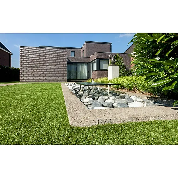 Kunstrasen Meterware Bali - Breite: 200 cm, Grün, Ohne Drainagenoppen - Außenansicht eines modernen Hauses mit einem dekorativen Wasser- und Steingarten im Vordergrund. Das Haus zeichnet sich durch seine klare Linienführung und Ziegelarchitektur aus.