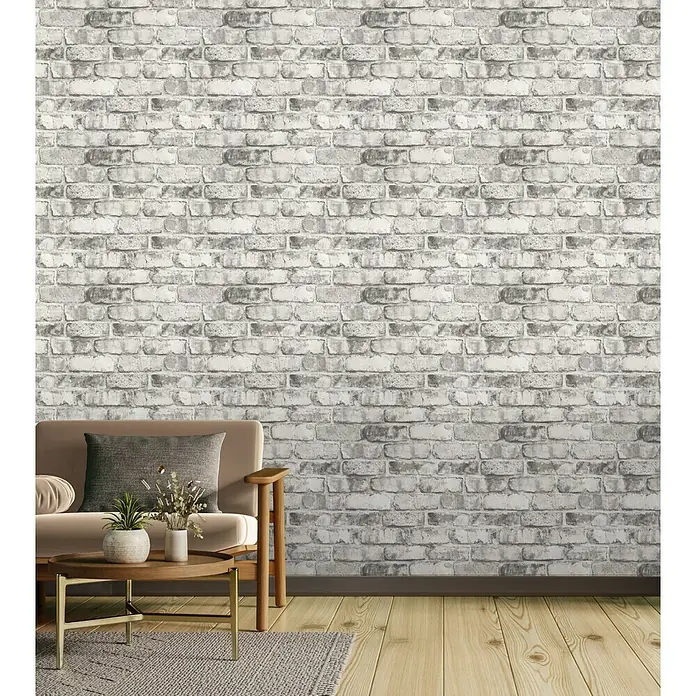 Tesa Rasch Strukturtapete Clayton Backstein - Selbstklebend, Grau, Steinoptik, 6 x 0,53 m - Ein Wohnzimmer mit einem Sofa, einem Couchtisch und einem Teppich vor einer Wand mit Backsteintapete. Die Backsteintapete dominiert den Raum.