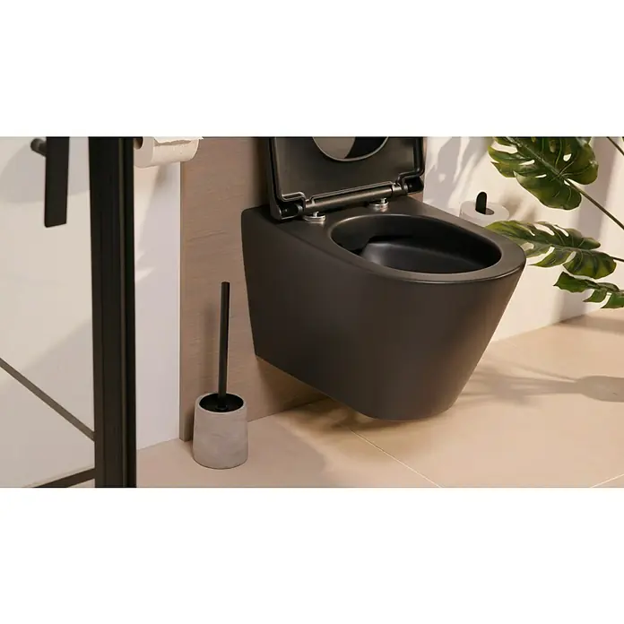 Wenko WC-Bürstengarnitur VillenaBeton, Grau - Ein modernes, wandhängendes WC in Mattschwarz mit offenem Deckel und passender Toilettenbürste neben einer Duschkabine und Dekopflanze.
