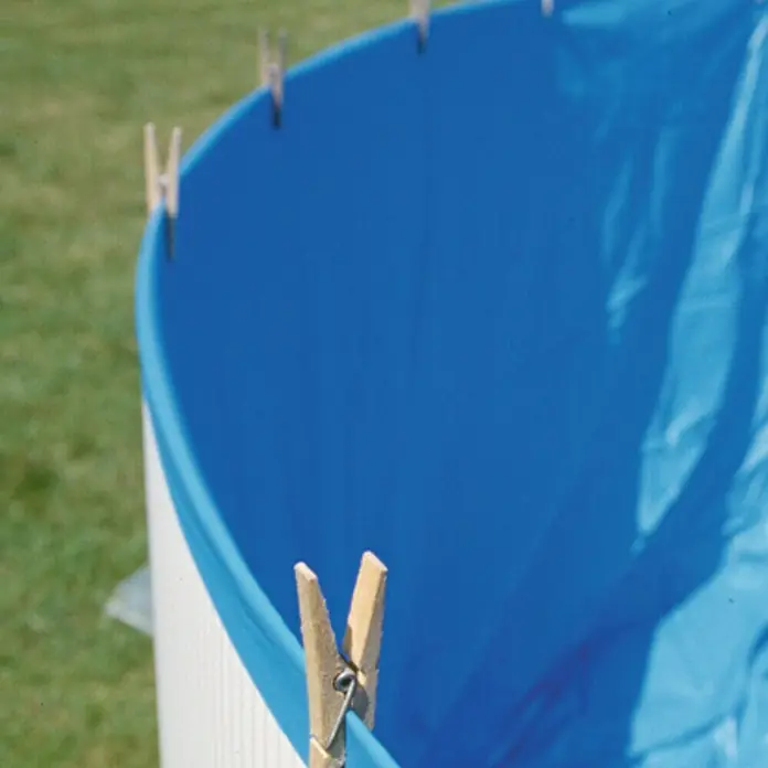 Gre Liner para piscina Overlap - Diámetro: 450 cm, Espesor de material: 20 µm - Primer plano de un revestimiento de piscina azul asegurado a un marco blanco con pinzas de la ropa. Atención al método de fijación.