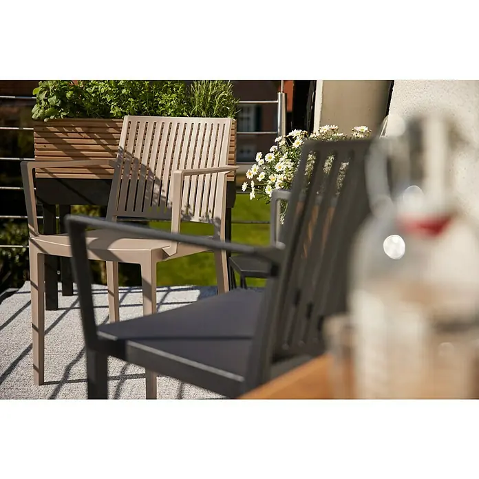 Siena Garden Urban Lights Gartenmöbel-Set Lane Sessel/Paco Tisch - 3 -tlg., Polypropylen, Taupe/Anthrazit - Blick auf zwei Gartenstühle auf einem Balkon, wobei der vordere Stuhl im Fokus steht. Die Szene wird durch Pflanzen und eine entspannte Atmosphäre ergänzt.