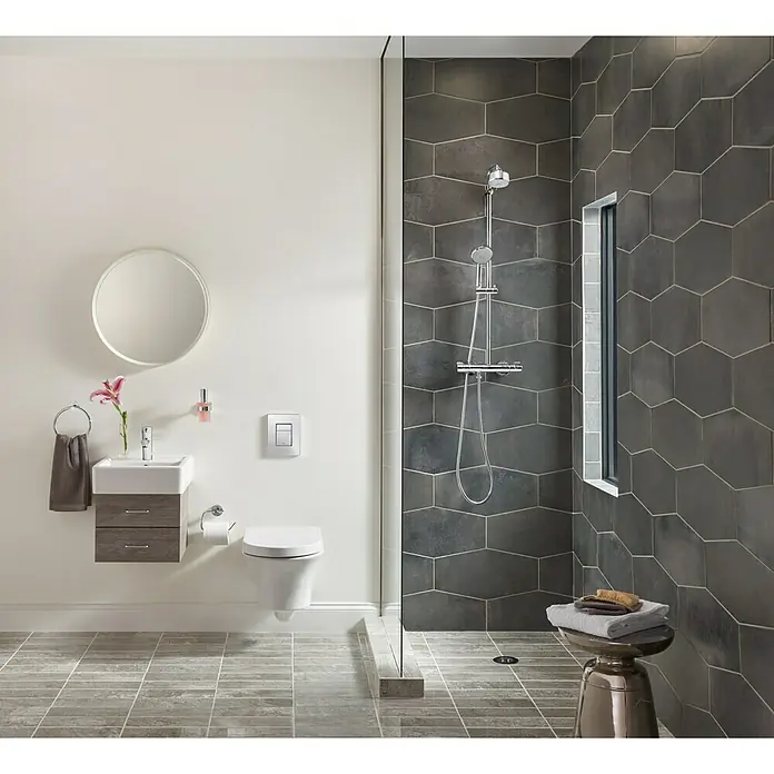 Grohe Essentials Toilettenpapierhalter - Ohne Deckel, Chrom, Glänzend - Ein modernes Badezimmer mit dunklen, sechseckigen Fliesen in der Dusche und einem schwebenden WC mit Spülkasten.