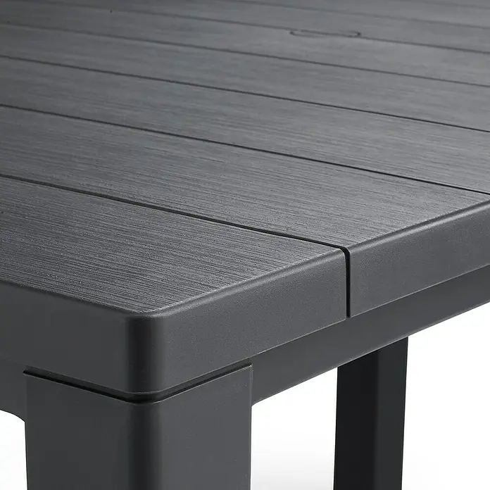Keter Mesa de jardín Julie - L x An x Al: 149 x 92 x 75 cm, Polipropileno, Grafito - Primer plano de una mesa de patio gris carbón con diseño de listones y patas robustas, ideal para uso en exteriores.