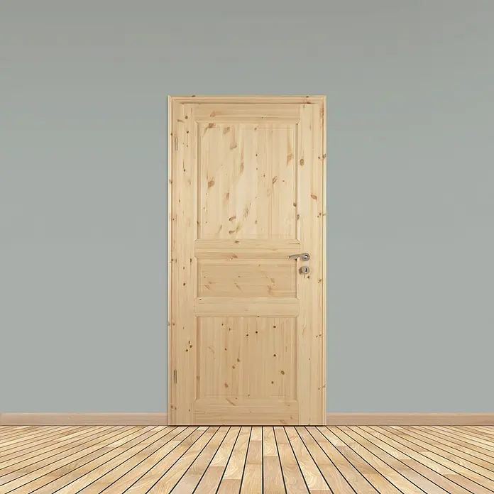 Kilsgaard Landhaustür 02/03 - 610 x 1.985 mm, DIN Anschlag: Links, Kiefer natur - Eine helle Holztür mit Paneelen und silberfarbenem Griff steht vor einer grauen Wand mit Holzboden.