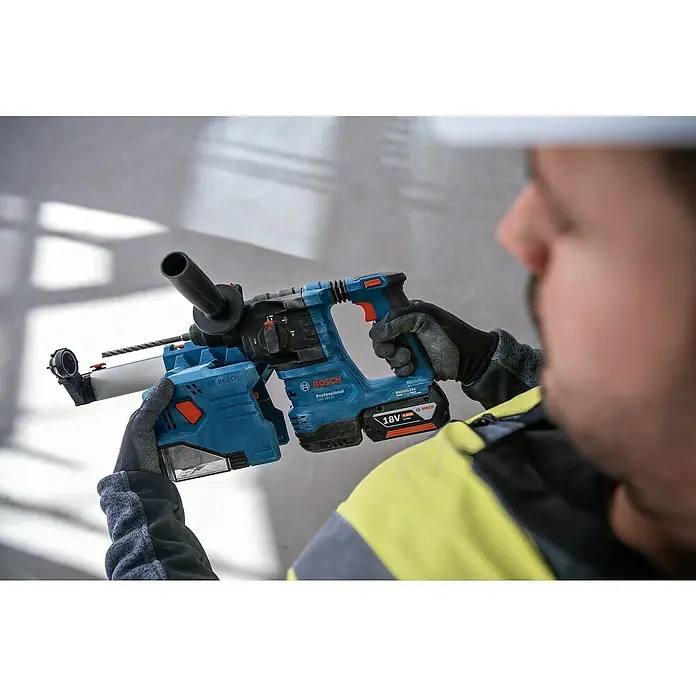 Bosch Professional AMPShare 18V Maschinen-Set 3-Tool-Kit - 18 V, 2 Akkus, 2 Ah - 4 Ah, 7 -tlg. - Nahaufnahme eines Bauarbeiters, der einen blauen Bosch Professional Akku-Bohrhammer mit Staubabsaugung vor einer Wand hält.