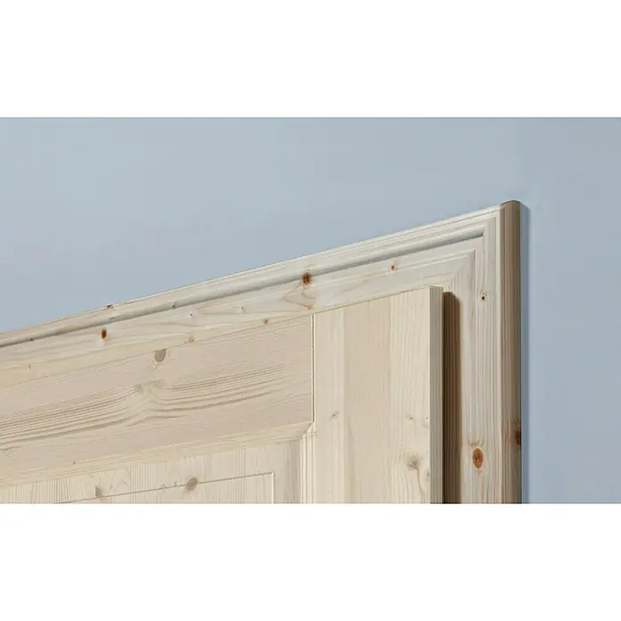 Kilsgaard Türzarge profiliert - 735 x 1.985 mm, Wandstärke: 100 mm, DIN Anschlag: Links, Kiefer Natur - Detailaufnahme einer hellen Holztür mit Zierleisten vor einer blauen Wand. Die Maserung des Holzes ist gut sichtbar.