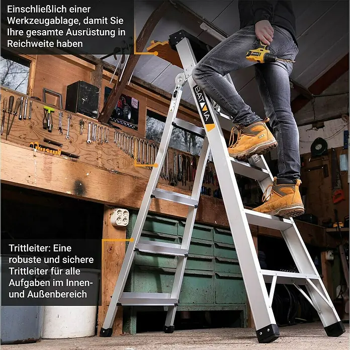Batavia Mehrzweckleiter - Anzahl Tritte: 9 Stk. - Robuste silberne Aluminium-Klappleiter mit gelbem Werkzeugfach, im Einsatz in einer Werkstatt.