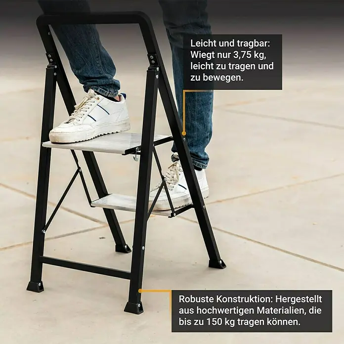 Batavia Stehleiter 2 Stufen - Anzahl Tritte: 2 Stk., Belastbarkeit: 150 kg - Schwarzer Klapptritt mit silbernen Stufen, von einer Person benutzt. Leicht (3,75 kg) und robust (150 kg Tragkraft).