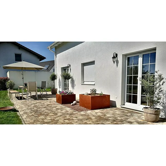 Palatino Exclusive Line Pflanzkasten Clara - 80 x 80 x 50 cm, Cortenstahl, Rotbraun - Außenaufnahme mit zwei quadratischen Pflanzkästen auf einer Terrasse, die mit roten Zierkieseln und Pflanzen dekoriert sind.