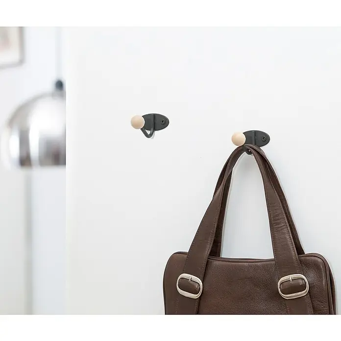 Rei Garderobenhaken C5294 - L x B x H: 36 x 50 x 65 mm, Stahl, Schwarz - Zwei Wandhaken mit schwarzen Metallbasen und hellen Holzkugeln, einer davon hält eine braune Ledertasche.