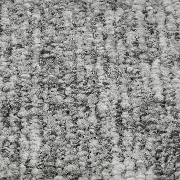 Teppichfliese Realise - Schlinge, 100 % Polypropylen, Silver - Detailaufnahme eines grauen Teppichs mit hoher Textur. Die Fasern sind dicht und unregelmäßig, was dem Teppich ein weiches Aussehen verleiht.
