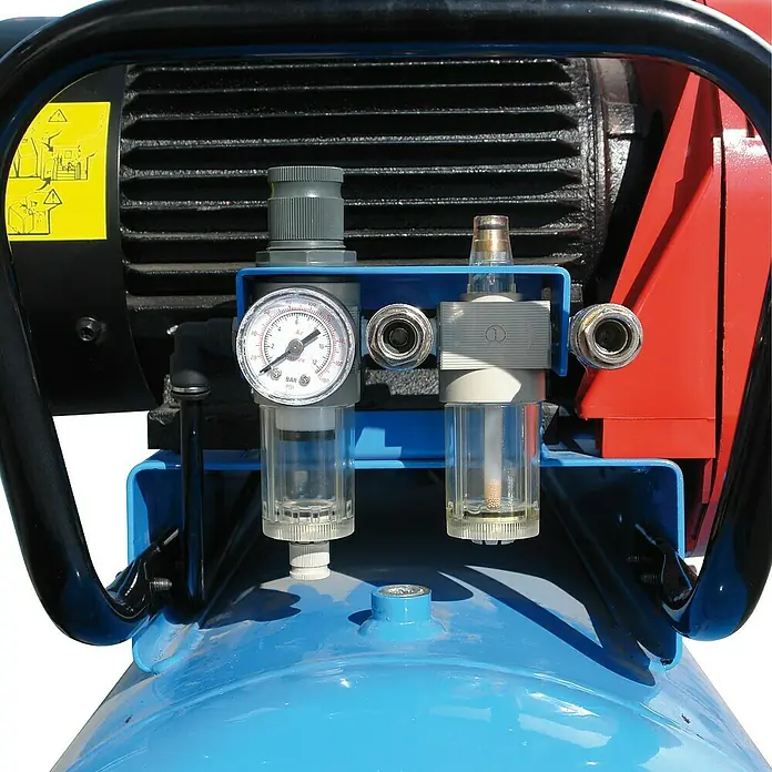 Güde Kompressor 635/10/90 Pro - 3.000 W, Max. Druck: 10 bar, 100 l, Schmierung: Ölgeschmiert - Blauer Luftbehälter eines Kompressors mit Manometer, Luftfilter, Regler und Schnellkupplungen, vor schwarzen und roten Maschinenteilen.