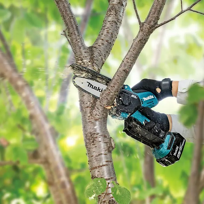 Makita LXT 18V Akku-Astsäge DUC150Z - 18 V, Li-Ionen, Ohne Akku, Schwertlänge: 15 cm - Nahaufnahme einer Makita Akku-Kettensäge beim Beschneiden eines Astes im Freien, Fokus auf die Säge.