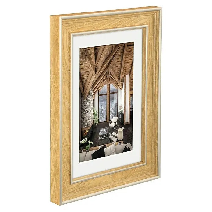 Hama Kunststoffrahmen Rustic - 13 x 18 cm, Eiche - Zweischichtiger heller Holzbilderrahmen mit weißem Innenpassepartout, der eine Winterhütten-Szene zeigt.