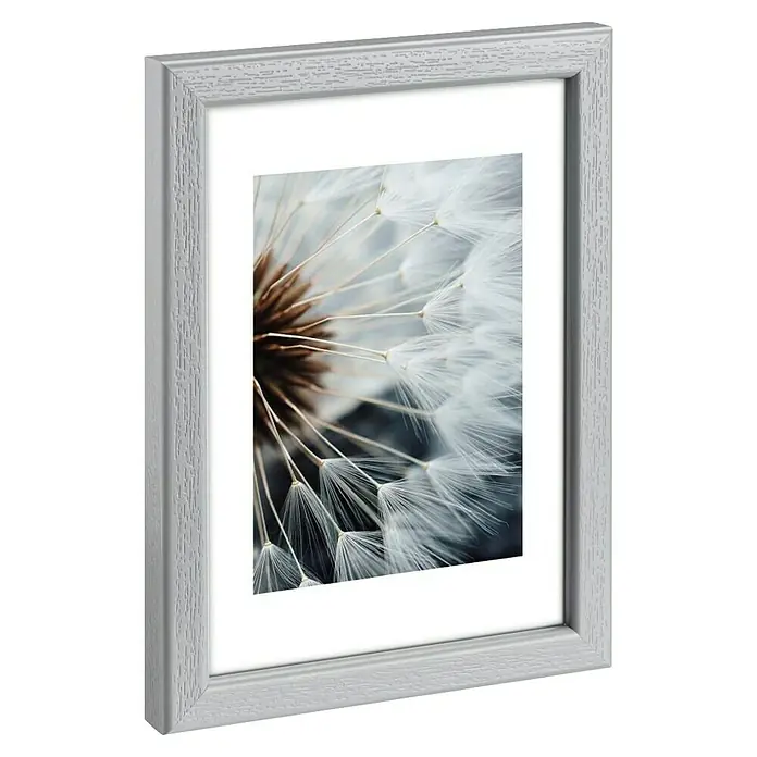 Hama Kunststoffrahmen Breeze - 15 x 20 cm, Grau - Weißer Holzbilderrahmen mit strukturierter Oberfläche, der ein Makrofoto einer Pusteblume zeigt.