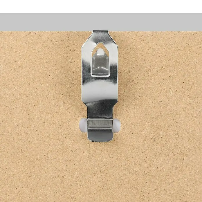 Hama Rahmenloser Bilderrahmen Clip-Fix Poly - DIN A4 (21 x 29,7cm), Acrylglas - Nahaufnahme einer silberfarbenen Bilderhängevorrichtung auf einer Holzoberfläche, ideal zum Aufhängen von Bildern und Dekorationen.