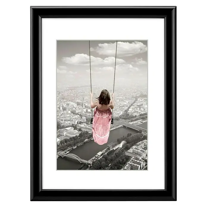 Hama Kunststoffrahmen Swing - 20 x 30 cm, Schwarz - Schwarz gerahmtes Bild einer Frau auf einer Schaukel hoch über einer Graustufen-Stadt mit rosa Kleid.