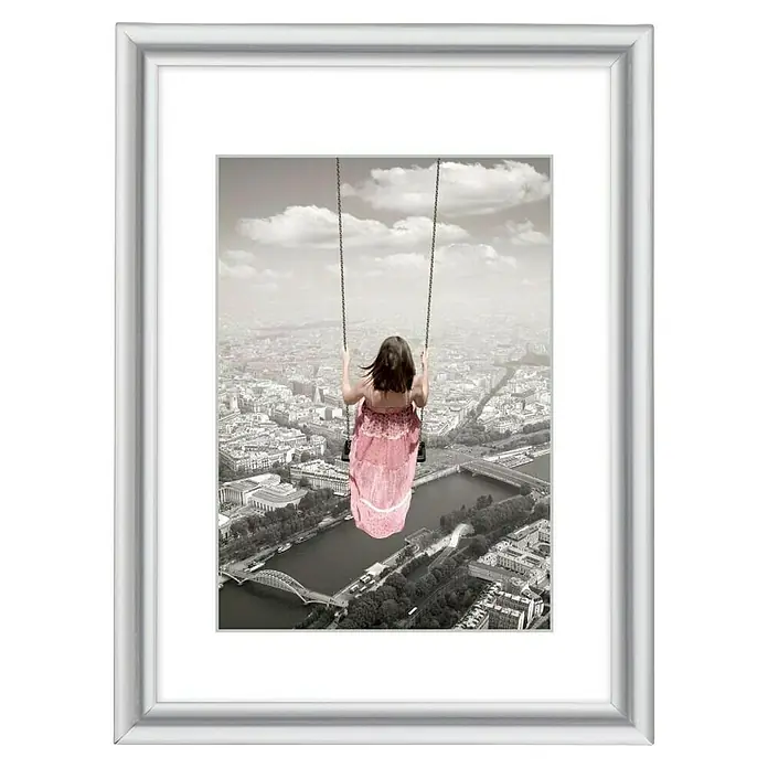 Hama Kunststoffrahmen Swing - 15 x 20 cm, Silber - Silberner gerahmter Druck mit einem Mädchen auf einer Schaukel über einer Stadt, mit weißem Passepartout.