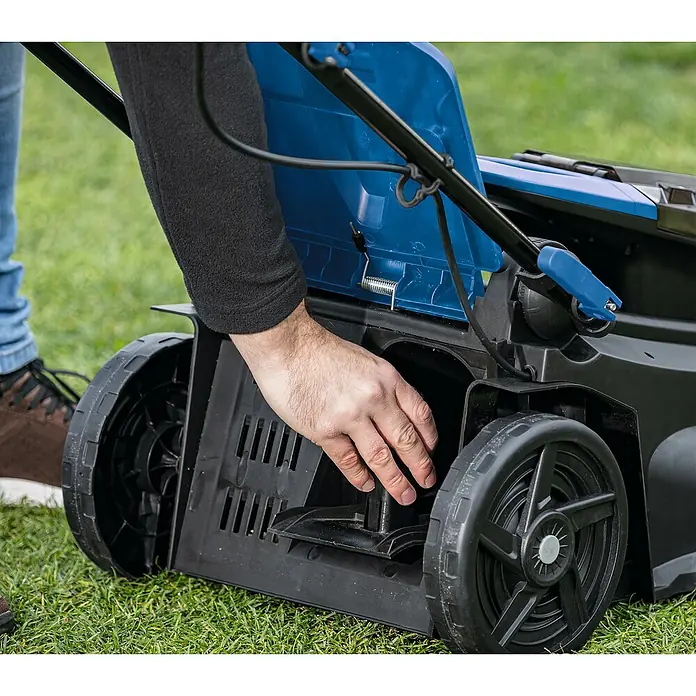 Scheppach IXES 20V Akku-Rasenmäher BC-MP380-X - 40 V, 2 Akkus, 4 Ah, Schnittbreite: 38 cm - Detailaufnahme eines Rasenmähers, bei dem eine Person den Fangkorb leert oder inspiziert. Der Rasenmäher ist blau und schwarz und steht auf Gras.
