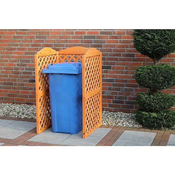 Promadino Mülltonnenbox Verkleidung Rex - 78,5 x 86,5 x 128 cm, Honigbraun - Eine blaue Mülltonne steht in einer hölzernen Mülltonnenbox im Freien, umgeben von einer Steinmauer und einem ordentlich gestutzten Baum.