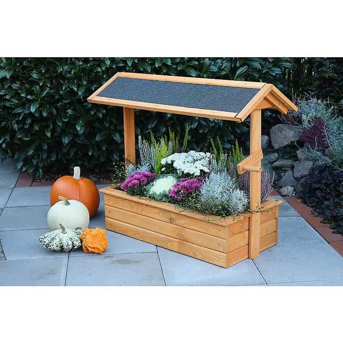Promadino Pflanzkasten Zierbrunnen Chiemsee - Außenmaß (L x B x H): 94,5 x 49 x 77 cm, Holz, Braun - Ein dekorativer Holzbrunnen mit Herbstblumen und Kürbissen, der eine festliche und einladende Atmosphäre schafft. Die Farben sind warm und einladend.